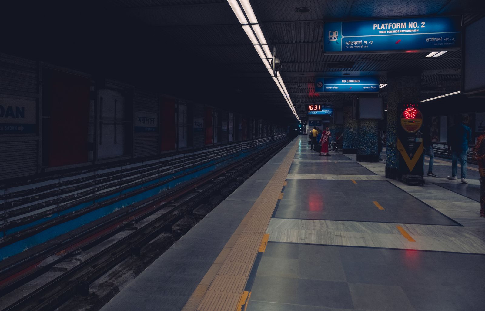 Passengers waiting on a dimly lit metro station platform